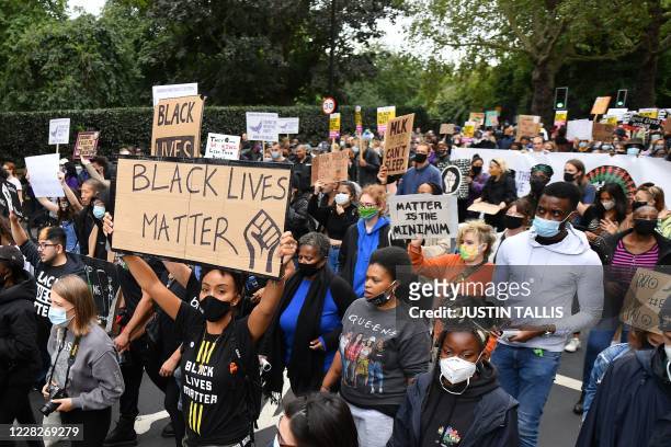 People hold up placards as they take part in the inaugural Million People March march from Notting Hill to Hyde Park in London on August 30 to put...