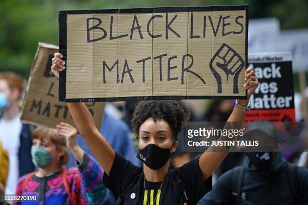 People hold up placards in support of the Black Lives Matter movement as they take part in the inaugural Million People March march from Notting Hill...