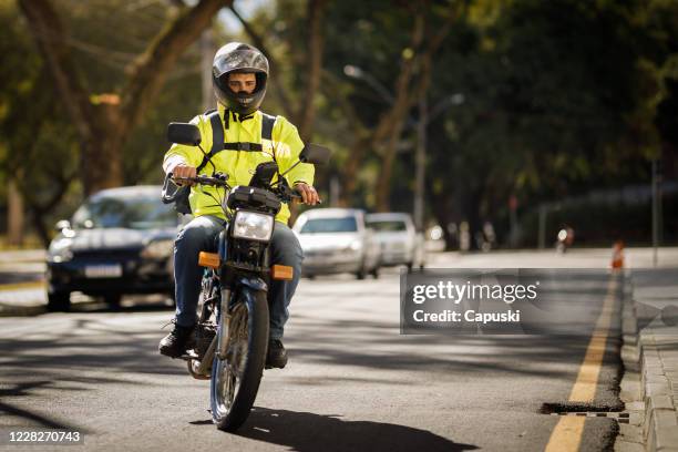 delivery biker riding down the street - motoboy - motorcycle biker stock pictures, royalty-free photos & images