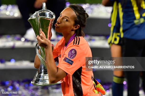 Lyon's French goalkeeper Sarah Bouhaddi kisses the winner's trophy as she celebrates with teammates after winning the UEFA Women's Champions League...