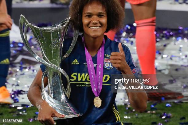 Lyon's French defender Wendie Renard poses with the trophy as Lyon's players celebrate after Lyon won the UEFA Women's Champions League final...