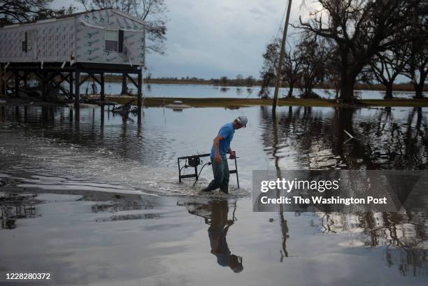 Tracy Miller carries an item through floodwater that is left after Hurricane Laura landed along the Texas-Louisiana border in Cameron, Louisiana on...
