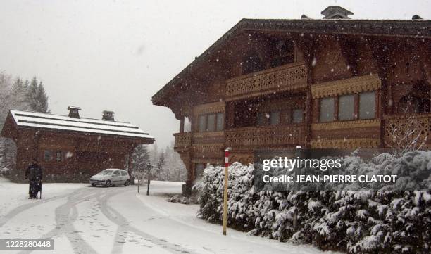 Une personne chargée de la sécurité passe avec son chien, le 27 novembre 2003 à Megève-Mont-d'Arbois, devant deux des chalets cambriolés du prince...