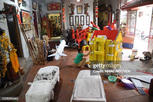 Woman painting a paper house as a religious offering at a family workshop in Hanoi on August 31, 2020 in preparation for the Hungry Ghost Festival. -...