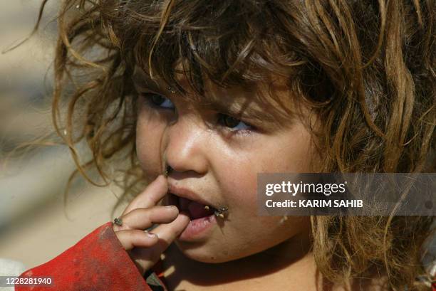 Ghagar or gypsy child with flies on her face is seen outside her home near a garbage dump in Taji, some 10 kms north of Baghdad 16 June 2004. Around...