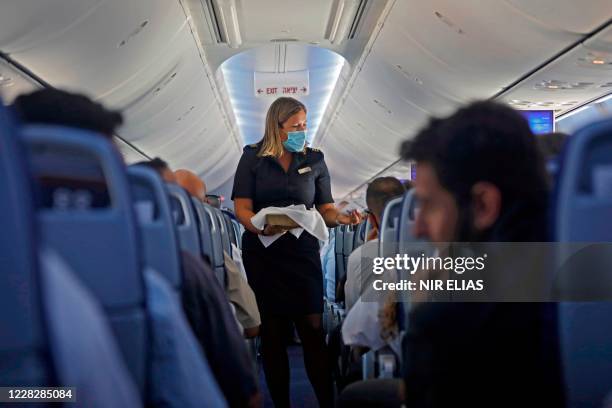 Flight attendant hands out chocolates with a greeting card to passengers on an El Al plane from Israel en route to Abu Dhabi, on August 31, 2020. - A...