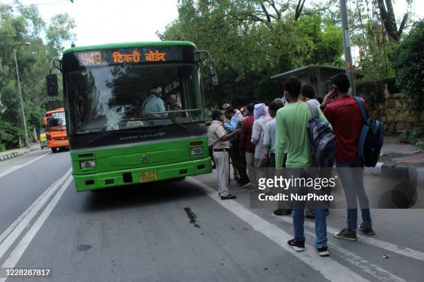Commuters queue to board DTC buses at Raj Ghat Power House near Delhi Secretariat on August 31, 2020 in New Delhi. India is fast becoming the world's...