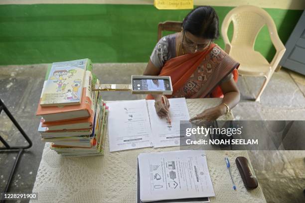 Headmistress M.C. Vijaya records worksheets on her mobile phone for the e-education classes at a government primary school in Nagireddypally Village...