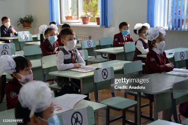 First grade students wearing face masks against the novel coronavirus sit on tables to begin their education as Kyrgyzstan government opens schools...