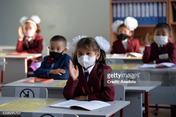 First grade students wearing face masks against the novel coronavirus sit on tables to begin their education as Kyrgyzstan government opens schools...