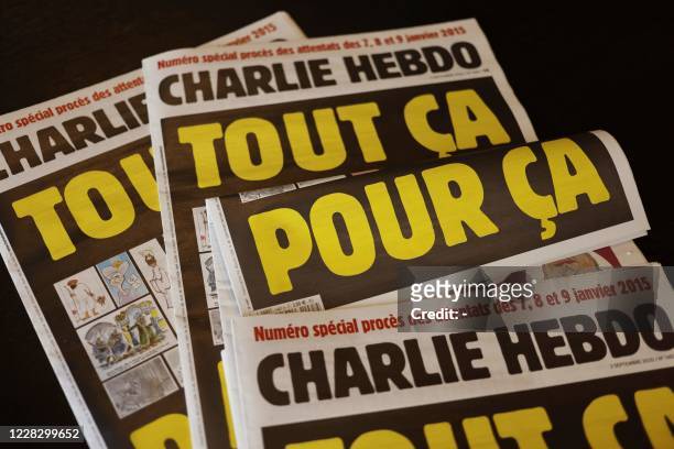 This picture taken on September 1, 2020 in Paris shows covers of French satirical weekly Charlie Hebdo reading "All of this, just for that," to be...