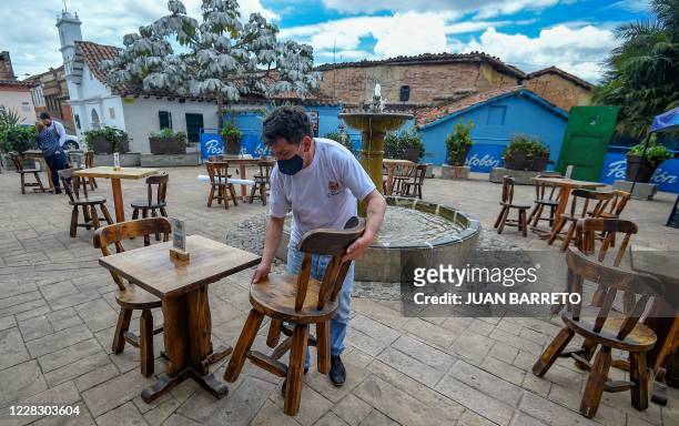 An employeewearing a face mask prepares tables, during a pilot test of restaurants opening in Chorro de Quevedo tourist area in Bogota on September 1...