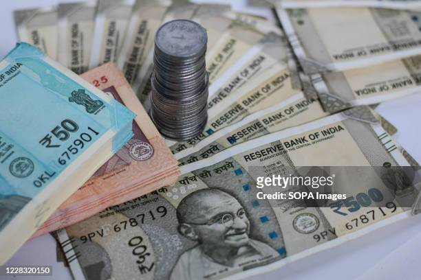 In this photo illustration five hundred rupee notes are seen with coins and fifty rupee notes.