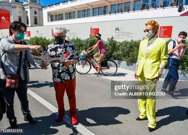 Spanish director Pedro Almodovar signs an autograph for a fan as British actress Tilda Swinton looks on, while on their way walking to attend a...