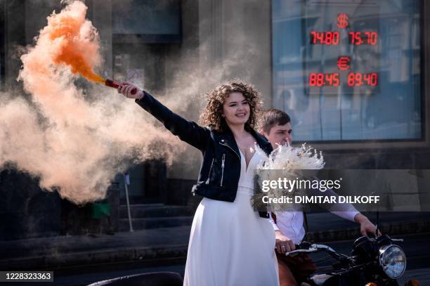 Newly married couple poses for a wedding photo sesion near a screen displaying the currency exchange rate of the Russian ruble with U.S. Dollar and...