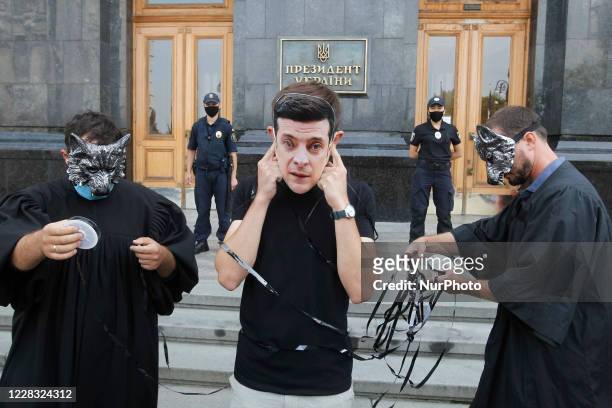 Activists who symbolic portray Ukrainian President Volodymyr Zelensky and judges in masks of wolves participate in a performance during a rally...