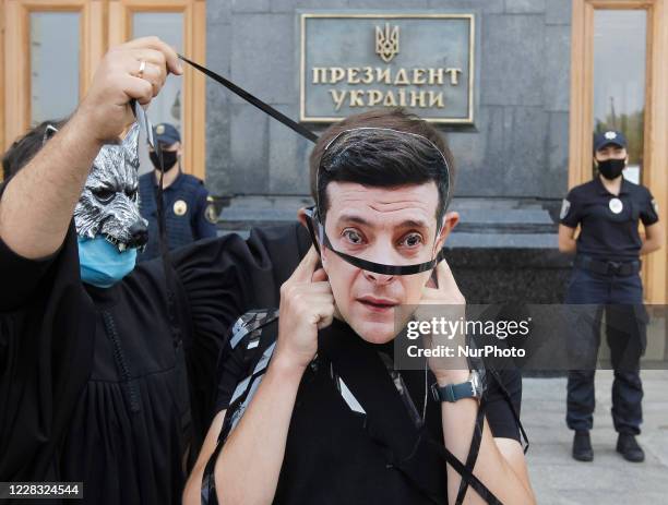 Activists who symbolic portray Ukrainian President Volodymyr Zelensky and judges in masks of wolves participate in a performance during a rally...