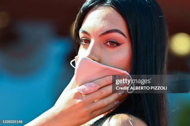 Argentinian-Spanish model and actress Georgina Rodriguez holds her face mask as she arrives for the screening of the film "The Human Voice" presented...