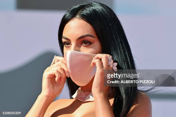 Argentinian-Spanish model and actress Georgina Rodriguez holds her face mask as she arrives for the screening of the film "The Human Voice" presented...