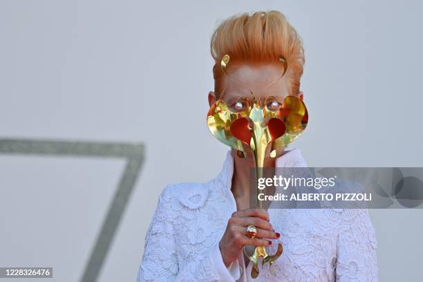 British actress Tilda Swinton holds a golden masquerade mask as she arrives for the screening of the film "The Human Voice" presented out of...