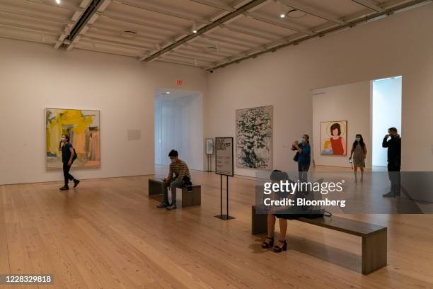 Visitors wearing protective masks walk through a gallery during the public reopening of the Whitney Museum of American Art in New York, U.S., on...