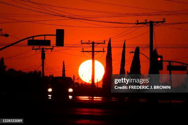 The sun sets behind power lines in Los Angeles, California on September 3 ahead of a heatwave to arrive September 4 through the Labour Day weekend...