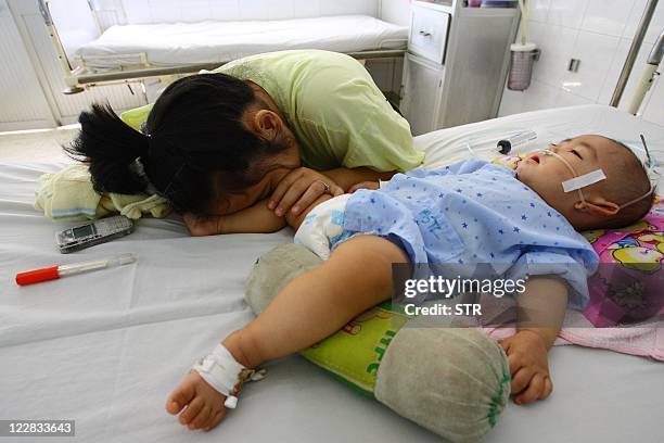 Nine-month-old boy Dao Xuan T, from the southern province of Binh Duong and affected by hand, foot and mouth disease, lies on a bed next to his...