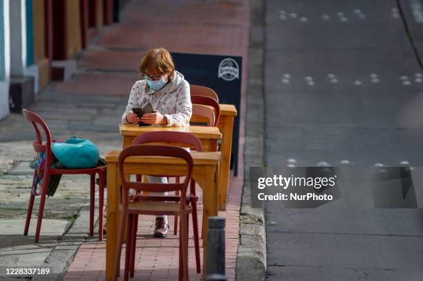 Woman waits for her lunch outiside of a restaurant located in the Candelaria neighboorhood, as part of the pilot to re open restaurants, Bogota, Open...