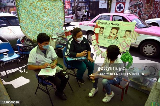 Volunteer Fatima Rodriguez speaks with Maria Luisa Moreno and her son Marcos Hernandez at the improvised street classroom called "Rinconcito de...