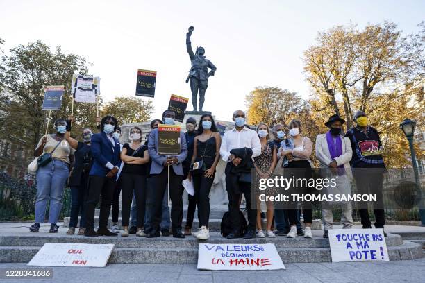 Head of SOS Racisme anti-racist NGO Dominique Sopo and other people, wearign face masks, hold signs as they gather in protest near the Valeurs...