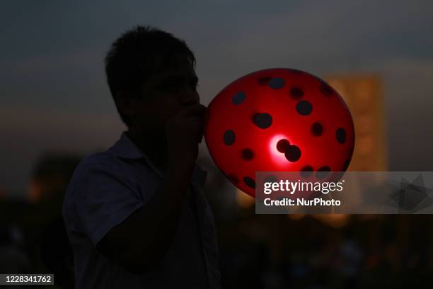 Street hawker blowing balloon at a park in Dhaka, Bangladesh on September 4, 2020.