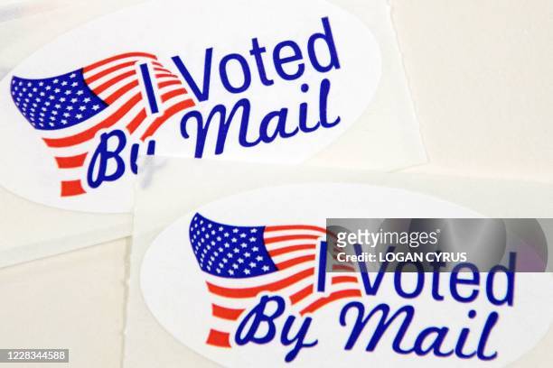 Stickers that read "I Voted By Mail" sit on a table waiting to be stuffed into envelopes by absentee ballot election workers at the Mecklenburg...