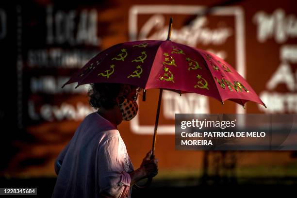 Woman holds an umbrella adorned with the hammer and sickle communist symbol during the Portuguese Communist Party Avante festival in Seixal,...