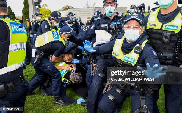 Police tackle protesters in Melbourne on September 5, 2020 during an anti-lockdown rally protesting the state's strict lockdown laws as a preventive...