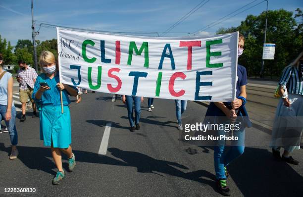 People wearing protective face masks hold a banner during the great march for climate change on September 5, 2020 in Warsaw, Poland. A few thousand...