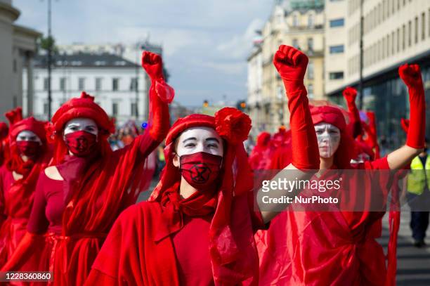 Extinction Rebellion activists dressed in red gowns as part of the Red Rebel Brigade rise their fists during a march against climate change on...