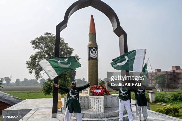 Political activists wave the Pakistani national flag in front of the Martyrs' Memorial monument in Lahore on September 6 to mark the country's...