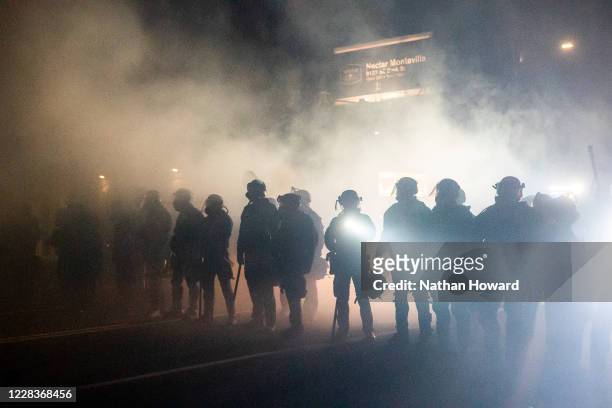 Oregon State Troopers and Portland police advance through tear gas while dispersing a protest against police brutality and racial injustice on...