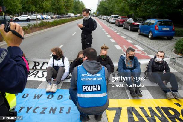 Climate activists sit in the middle of the street while police officers from the anti conflict team try to persuade them to leave on September 7,...