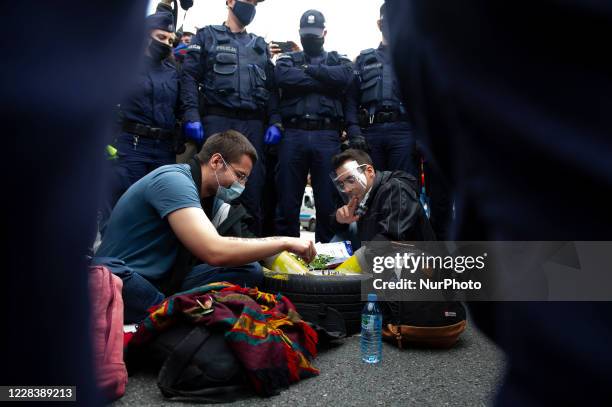 Climate activists, surrounded by police officers, hold onto a car tire filled with concrete while playing chess during a civil disobedience action on...