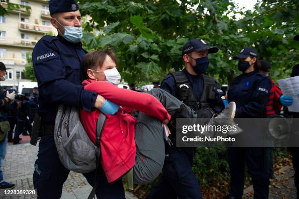 Police officers carry a climate activist which was blocking a street during a civil disobedience action on September 7, 2020 in Warsaw, Poland. A few...