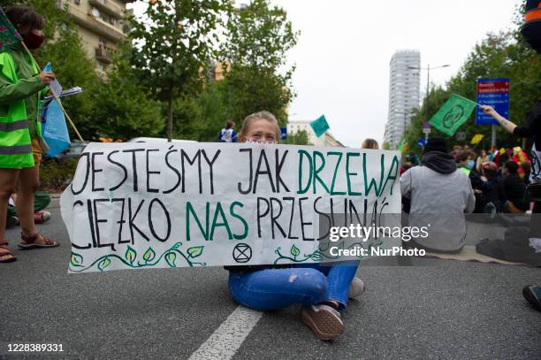 Climate activist holds a banner that reads &quot;we are like trees, it is hard to move us&quot; during a civil disobedience action on September 7,...