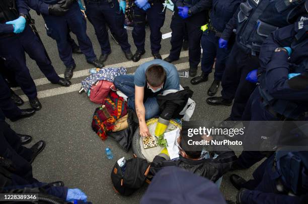 Climate activists, surrounded by police officers, hold onto a car tire filled with concrete while playing chess during a civil disobedience action on...