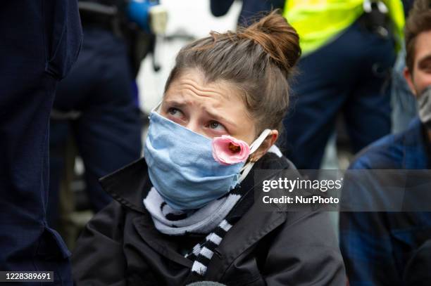 Climate activist wearing a protective face mask looks at police officers during a protest on September 7, 2020 in Warsaw, Poland. A few hundred...