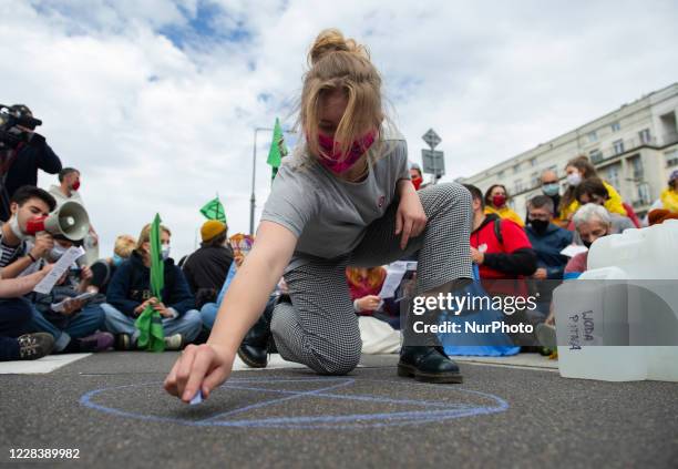 Climate activist draws on the asphalt an Extinction Rebellion logo during a civil disobedience action on September 7, 2020 in Warsaw, Poland. A few...