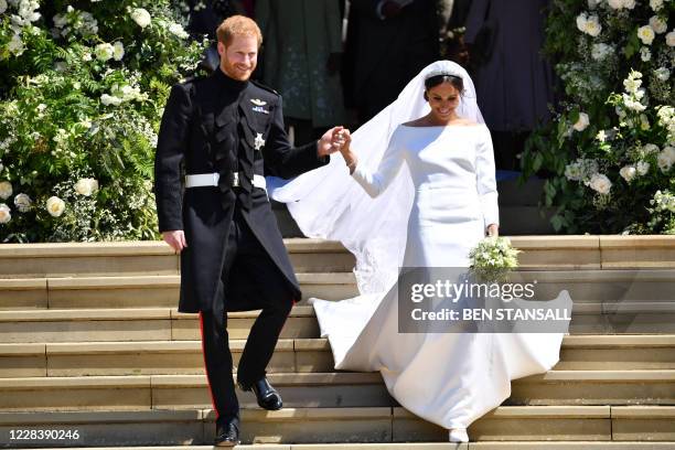 In this file photo taken on May 19 Britain's Prince Harry, Duke of Sussex and his wife Meghan, Duchess of Sussex emerge from the West Door of St...