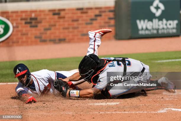 Adeiny Hechavarria of the Atlanta Braves is tagged out at home by Jorge Alfaro of the Miami Marlins in the seventh inning of a game at Truist Park on...