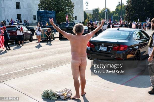 Naked Black Lives Matter demonstrator holds middle fingers up toward right wing demonstrators after a pro-Trump caravan rally convened at the Oregon...