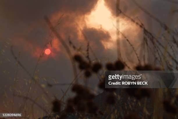 The sun is seen behind smoke from the Bobcat fire rising above in the Angeles National Forest above Duarte, California, about 27 miles northeast of...