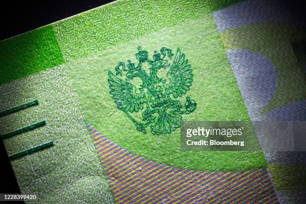 The Russian imperial double-headed eagle coat of arms, the emblem of Russia's central bank, sits on a ruble banknote in this arranged photograph in...